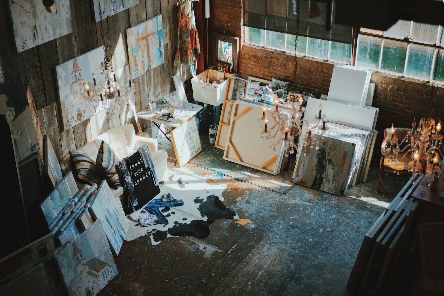 Atelier d'artiste avec des toiles et du matériel éparpillés au sol.