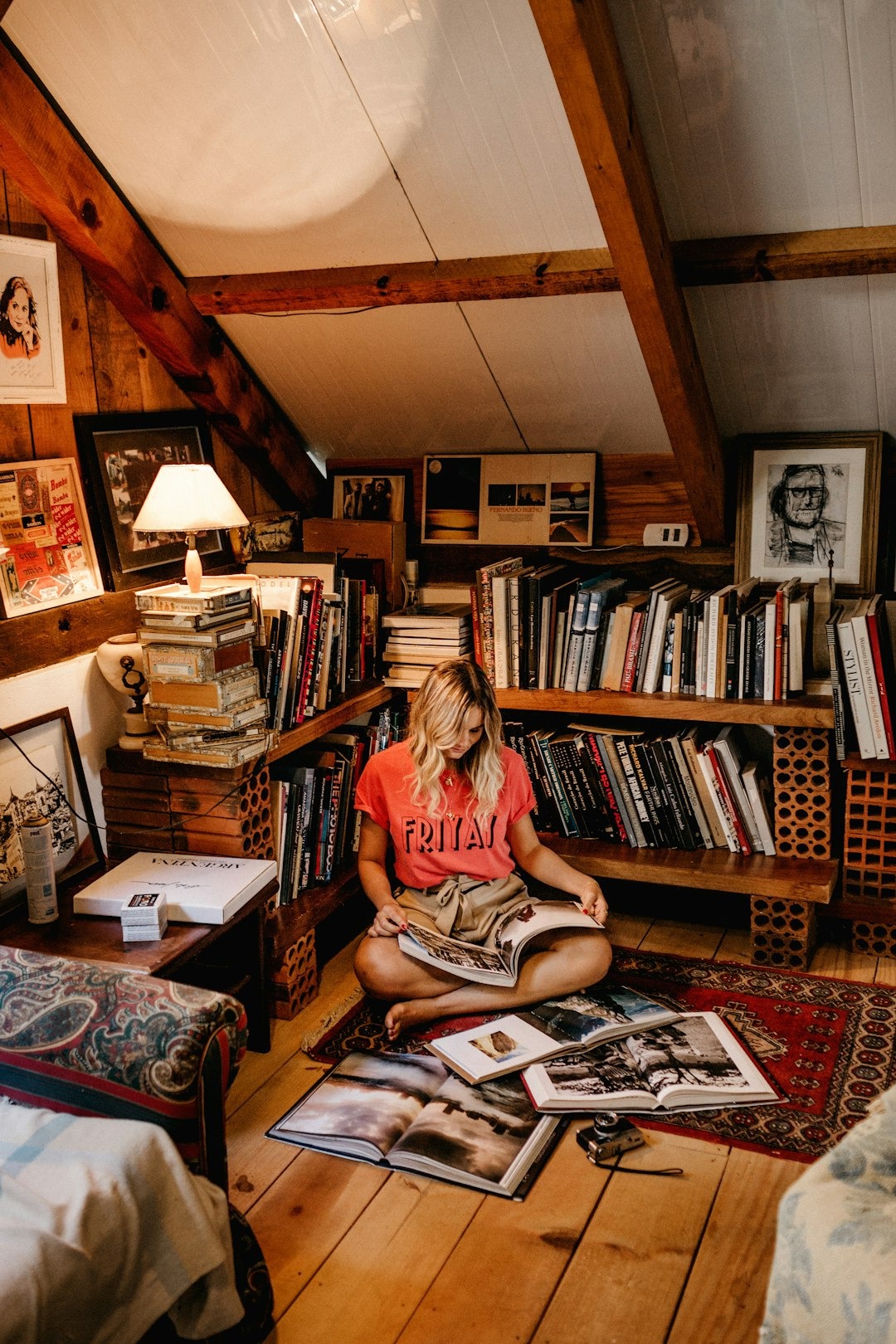 Woman reads a book in a cozy, book-filled attic room.
